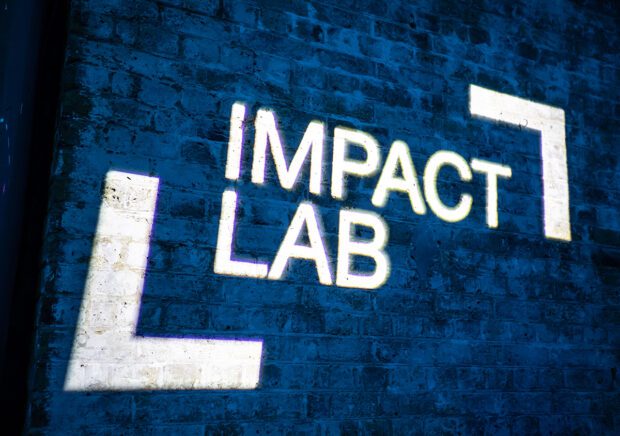 Impact Lab logo projected onto brick wall